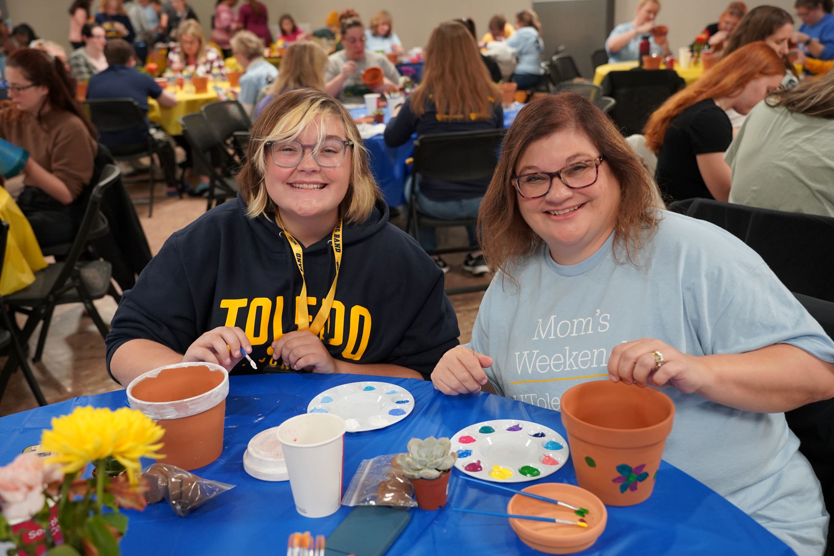Mother and daughter during Mom's Weekend painting flower pots.