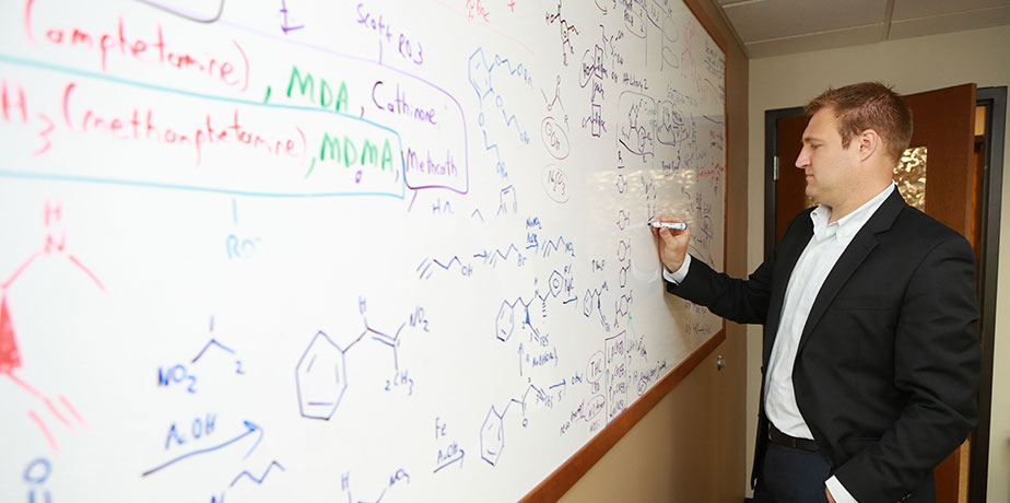 Isaac Schiefer working out an equation on a white board