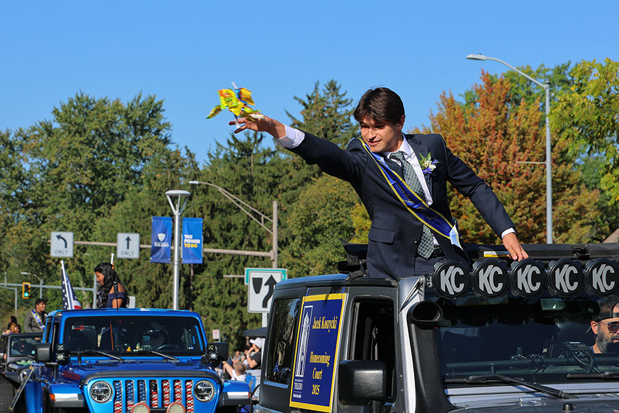 member of homecoming court throwing candy out of a jeep during parade
